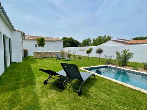 une cour avec deux chaises et une piscine dans l'établissement La Villa Mirabelle, à Loix