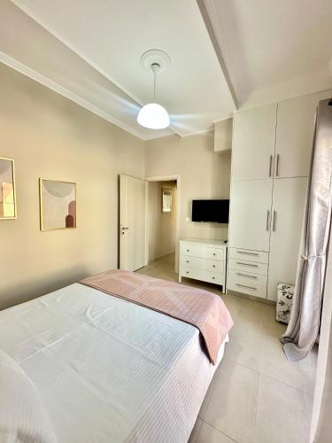 a bedroom with a large white bed and a television at Aiginetan Apartments in Aegina Town