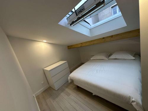 ein Schlafzimmer mit einem weißen Bett und einem Dachfenster in der Unterkunft Studio indépendant proche de Paris in Vitry-sur-Seine