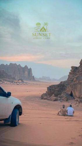 two people sitting in the desert next to a car at Sun Set Luxury Camp in Disah
