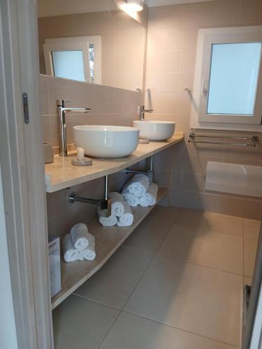 a bathroom with two sinks and towels on a shelf at Villa Ginepro in Olbia