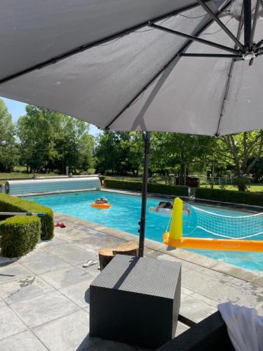un parasol installé en face d'une piscine dans l'établissement Chambres d'hotes à louer Le Mans Circuit 24H, à Étival-lès-Le Mans
