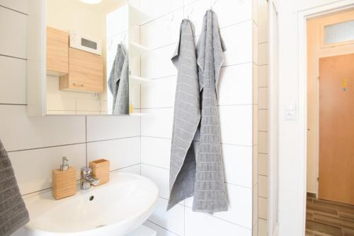 biała łazienka z umywalką i lustrem w obiekcie Vienna City Apartment Kempelengasse w Wiedniu