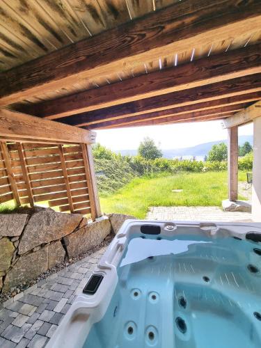 un bain à remous dans une arrière-cour avec un toit en bois dans l'établissement Chalet Terres Neuves, confort et vue sur le lac, à Gérardmer