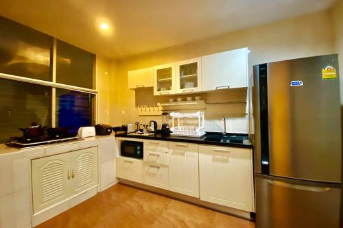 una cucina con mobili bianchi e un frigorifero in acciaio inossidabile di BTS Asoke 6bedroom townhouse a Bang Kapi