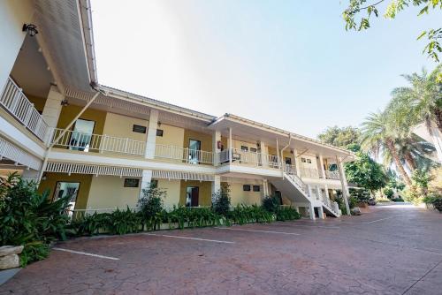 a large yellow building with a parking lot at Wangka Resort in Sangkhla Buri
