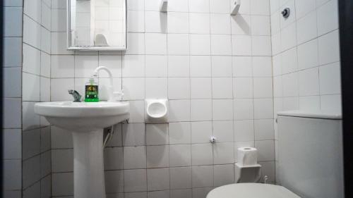 a white bathroom with a sink and a toilet at Chácara bello Rio in Guaratuba