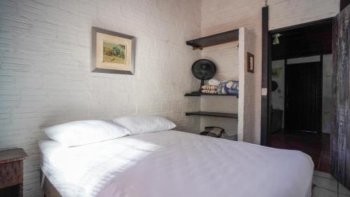 a bedroom with a white bed and a white brick wall at Chácara bello Rio in Guaratuba