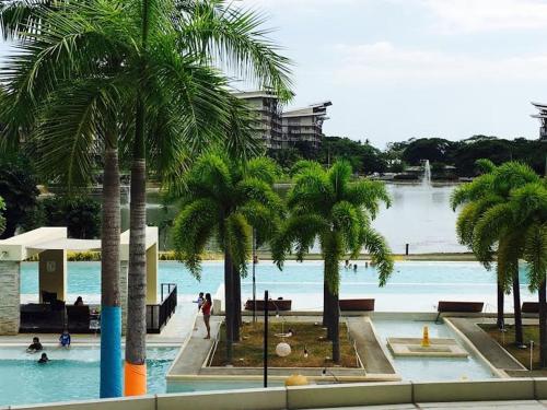 een zwembad met palmbomen en mensen in het water bij 409 at Jacana B Condominium in Nasugbu