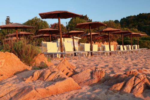 a group of chairs and umbrellas on a beach at Hotel Don Diego in Porto San Paolo
