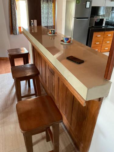 a kitchen with a counter with two stools and a island at La Maison Du Voyageur in Kribi