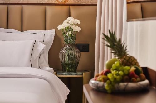a vase of flowers on a table with a bowl of fruit at Palazzo President in Split