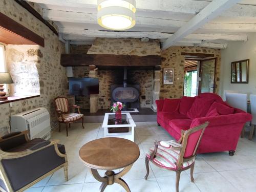 ein Wohnzimmer mit einem roten Sofa und einem Tisch in der Unterkunft Maison en pierre avec piscine in Billac