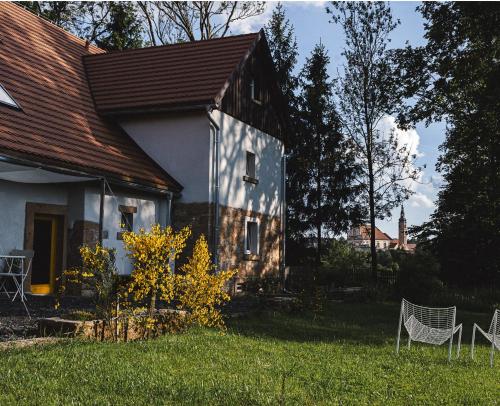 a white house with two chairs in the yard at Wietorówka in Lubomierz