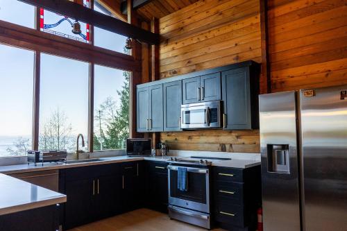 a kitchen with stainless steel appliances and wood walls at Port Hadlock Luxury Cabin Retreat Awaits you! cabin in Chimacum