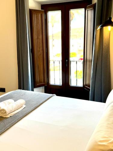 a bedroom with a bed with two towels on it at Barbarossa Suites Plaza de España in Merida