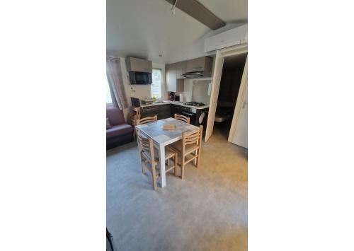 un salon avec une table et une cuisine dans l'établissement Mobil-home Clim, TV, LL Camping LA CARABASSE 4 étoiles - MH-A013, à Vias