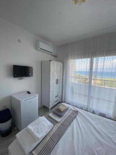 a white bedroom with a large bed and a television at Harmony Blue Pansiyon in Burhaniye