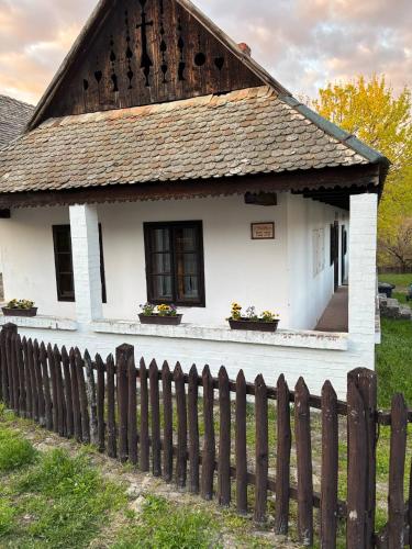an old white house with a wooden fence at Hollóköves Vendégházak in Hollókő