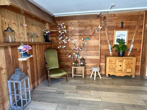 a room with a green chair and a wooden wall at Hôtel-Chalet les Mélèzes in Valloire