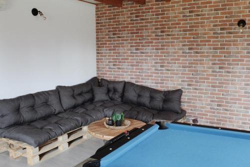 a living room with a black couch and a brick wall at La Casa d'Opale, maison de vacances 14 couchages in Montauban