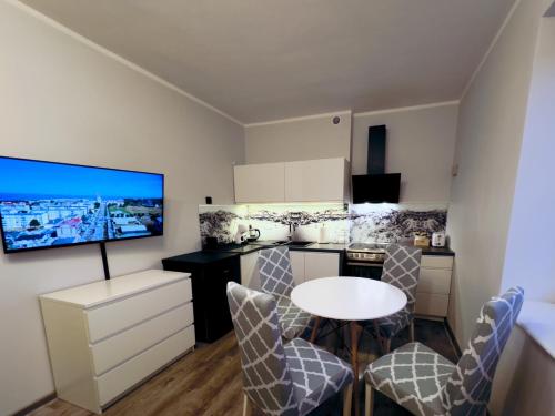 Una cocina con mesa y sillas y un televisor. en MorzePort Władysławowo, en Władysławowo