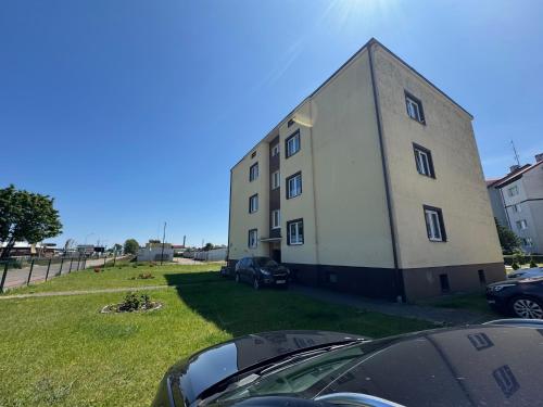 Un gran edificio con coches aparcados delante. en MorzePort Władysławowo, en Władysławowo