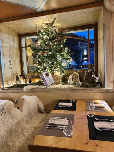 a christmas tree in a room with a table at Hôtel-Chalet les Mélèzes in Valloire