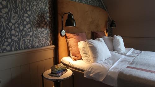 a bedroom with a bed and a side table with a lamp at Home Hotel Fregatten in Varberg