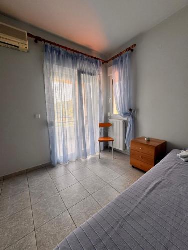 a bedroom with a bed and a chair and window at The Big Olive Tree in Hanioti