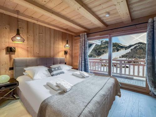 une chambre avec un grand lit et une grande fenêtre dans l'établissement 1/2 Chalet : douceur Alpine au Linga, à Châtel