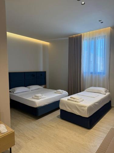 two beds sitting in a room with a window at ReiVal Hotel Marina Vlore in Vlorë