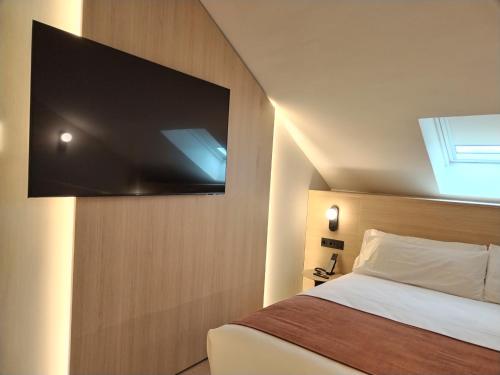 a bedroom with a bed with a flat screen tv on the wall at Aparthotel Atenea Calabria in Barcelona