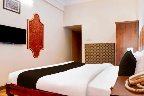 a bedroom with a large white bed and a desk at Hotel O Rai Ka Bagh Near Railway Station in Jodhpur