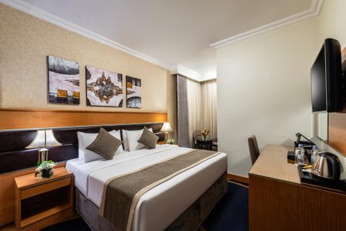 a hotel room with a large bed and a desk at Golden Tulip Al Shakreen in Al Madinah