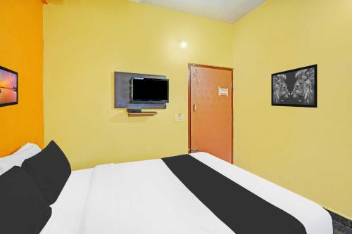 a bedroom with a bed and a tv on the wall at Hotel O Coorg in Kushālnagar