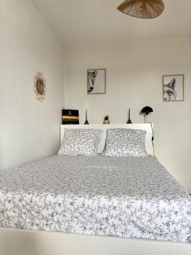 une chambre blanche avec un lit blanc avec un couvre-lit fleuri dans l'établissement Petit cocon avec terrasse, à Billère