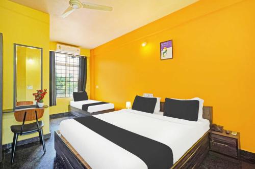 a bedroom with a large bed and a yellow wall at Hotel O Coorg in Kushālnagar