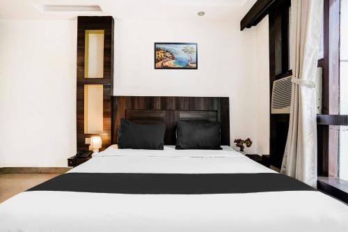 シルディにあるHotel O Shirdi Near Sai Baba Templeの木製のヘッドボードが付いた白いベッドのある寝室