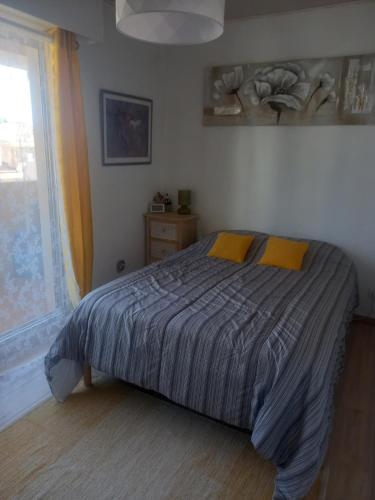 une chambre avec un lit avec des oreillers jaunes et une fenêtre dans l'établissement Logement atypique centre ville, à Sainte-Maxime