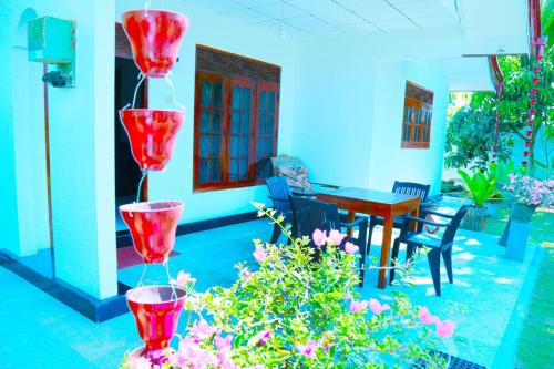a patio with red flowers and a table and chairs at Villa Serenity Weligama in Weligama
