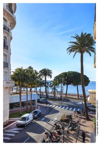 une rue avec des palmiers et une rue avec des voitures et des motos dans l'établissement REF 961 - Cannes Croisette - Sea view apartment for rent, à Cannes