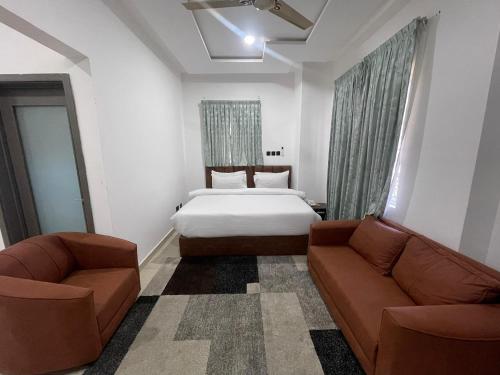 Plus 33 Hotel في Sakumona: غرفة فندق بها سرير وأريكتان