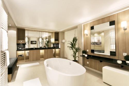 ein Bad mit einer großen weißen Badewanne in einem Zimmer in der Unterkunft Hotel Bayerischer Hof in Lindau