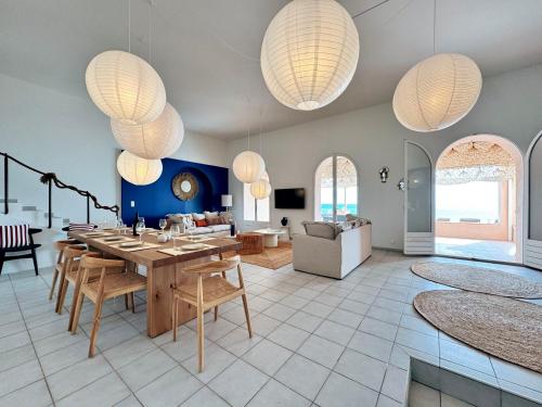 - un salon avec une table, des chaises et des lustres dans l'établissement Villa pieds dans l eau la Nartelle, à Sainte-Maxime