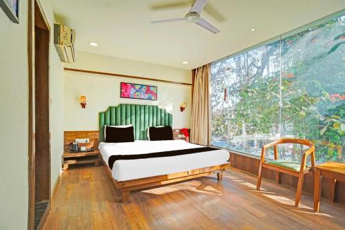 a bedroom with a bed and a large window at Hotel O Arvind Marg Pachamarhi in Pachmarhī