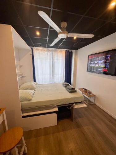 Cette chambre comprend un lit et un ventilateur de plafond. dans l'établissement A deux pas des plages, à Vallauris