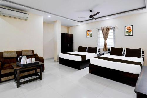 a bedroom with two beds and a table and a couch at Hotel O Tirumala Road Near Alipiri in Tirupati
