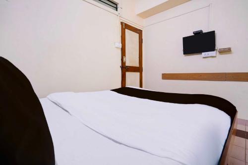 a bedroom with a white bed with a tv on the wall at Super Hotel O Hubli City Center in Hubli