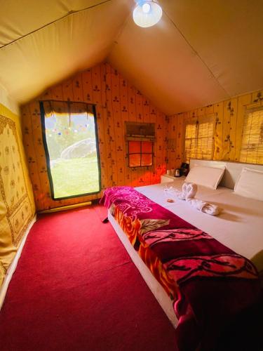 a bedroom with a large bed in a room with a window at Uphill Adventures and Meditation I Dharamshala in Dharamshala